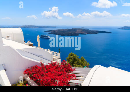 Une vue sur la caldeira et les fleurs rouges typique sur la terrasse d'une maison de village de Firostefani, Santorin, Grèce Banque D'Images