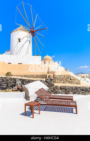 Deux chaises longues sur la terrasse et vue du célèbre Moulin dans le village d''Oia, Santorin, Grèce Banque D'Images