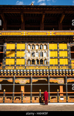 Le moine bouddhiste debout à côté de la réserve de galeries en bois entourant la cour intérieure du monastère à Paro Dzong, le Bhoutan Banque D'Images