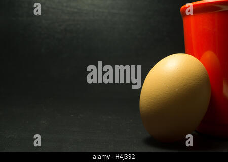 Oeuf jaune et rouge sur fond noir verre Banque D'Images