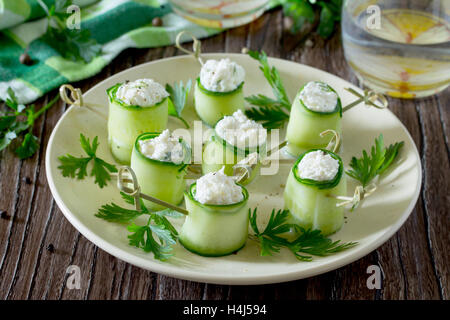 Rouleaux de concombre farci au fromage feta, olives et l'aneth sur une table en bois. Banque D'Images