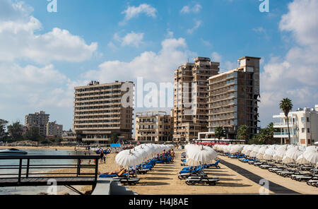 Palm Beach avec des parasols de plage et les touristes et les hôtels abandonnés à Varosha Ghost Town, Famagusta, Chypre du Nord Banque D'Images