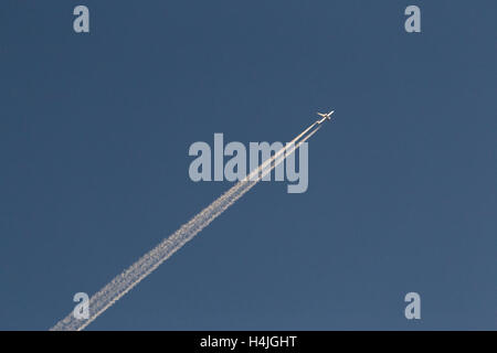 Les traînées de condensation d'avions à réaction con trails contre un ciel bleu clair Banque D'Images