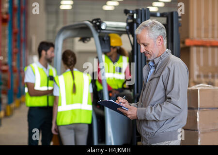 Warehouse Manager writing on clipboard Banque D'Images