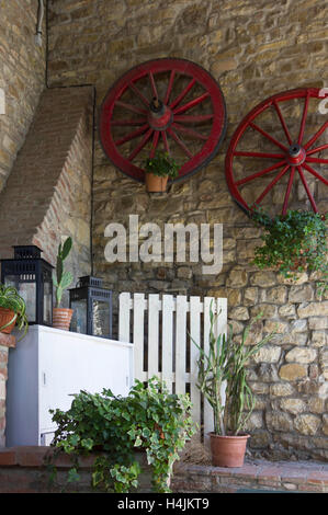Vintage corner dans un vieux restaurant de style en Toscane, Italie, avec les roues rouges accroché au mur Banque D'Images