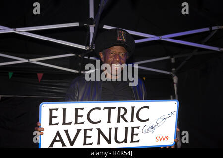 Brixton, UK. 17 Oct, 2016. Eddy Grant, musicien, est titulaire d'un chandail Electric Avenue Street signe comme il assiste à l'interrupteur sur des nouvelles lumières dans Electric Avenue Brixton après une rénovation récente du marché Crédit : Keith Larby/Alamy Live News Banque D'Images
