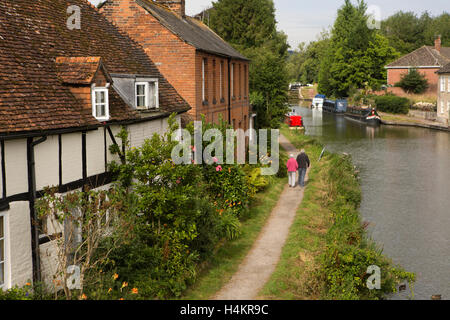 L'Angleterre, Berkshire, Hungerford, vieux couple walking cours des vieilles maisons sur chemin de halage au bord du canal de Kennet et Avon Banque D'Images