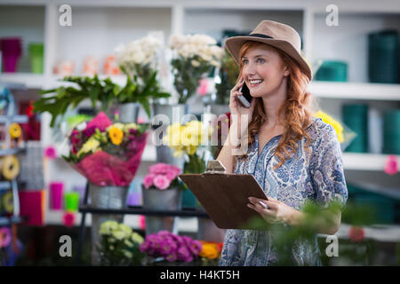 Female florist taking order on mobile phone Banque D'Images