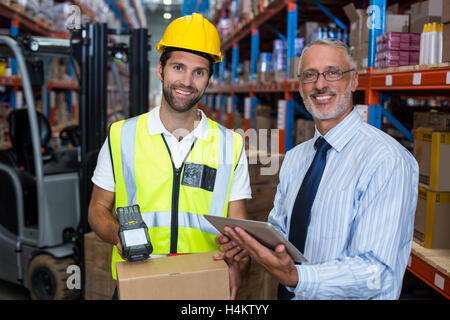 Warehouse Manager holding digital tablet while travailleur homme Barcode scanning Banque D'Images