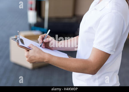 Mid section de livraison woman writing on clipboard Banque D'Images