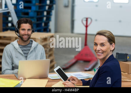 Portrait de gestionnaires d'entrepôt à l'aide d'ordinateurs portables et tablettes numériques Banque D'Images