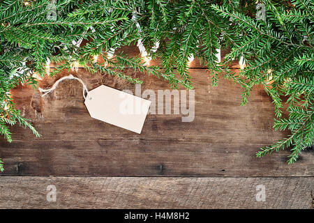 Arbre de Noël des branches de pins, carte vierge et des lumières décoratives sur un fond rustique en bois de grange. Droit coup de frais généraux. Banque D'Images
