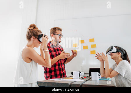 Équipe de développeurs qui travaillent avec des lunettes de réalité virtuelle lors d'une réunion d'affaires. Jeune homme avec des collègues de sexe féminin brainstormin Banque D'Images