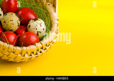 Oeufs de Pâques en panier sur fond jaune Banque D'Images