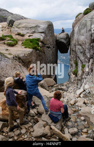 Les touristes de prendre des photos d'amis sur Kjeragbolten, un rock hanging 1100 mètres au-dessus du fjord Lysefjorden, Norvège Banque D'Images