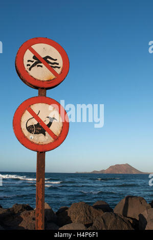 Fuerteventura : une affiche interdisant la baignade et la pêche dans le port de Corralejo avec vue sur la petite île de Lobos sur l'arrière-plan Banque D'Images