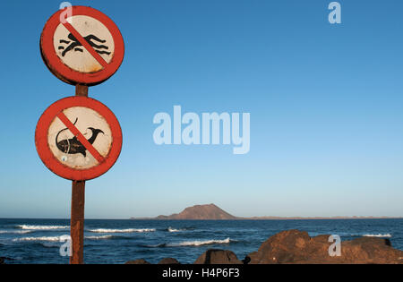 Fuerteventura : une affiche interdisant la baignade et la pêche dans le port de Corralejo avec vue sur la petite île de Lobos sur l'arrière-plan Banque D'Images