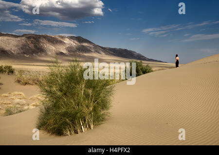 Femme en robe noire à la montagne à Ulkan Kalkan la chanson de Dune de sable avec Saxual arbres Kazakhstan Banque D'Images