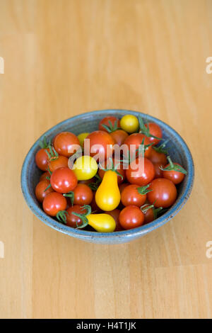 Lycopersicon esculentum. Un bol de tomates mûres sur une table en bois. Banque D'Images