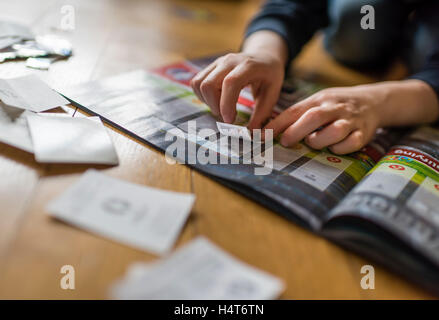 Un garçon de 8 ans est de coller les cartes de football dans sa collection autocollant album. Banque D'Images