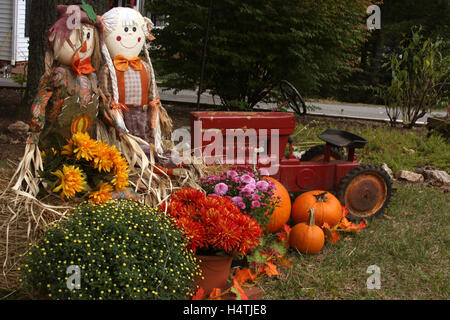 Décoration automne en plein air avec des épouvantails, mamans, tracteur, et les citrouilles Banque D'Images