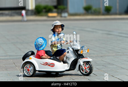 Frère et sœur équitation un jouet électrique combinaison moto sur Gengis Khan Square, Ulaanbaatar, Mongolie Banque D'Images