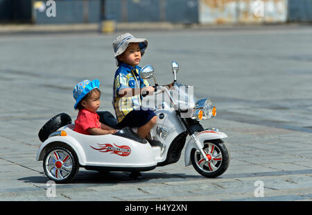 Frère et sœur équitation un jouet électrique combinaison moto sur Gengis Khan Square, Ulaanbaatar, Mongolie Banque D'Images