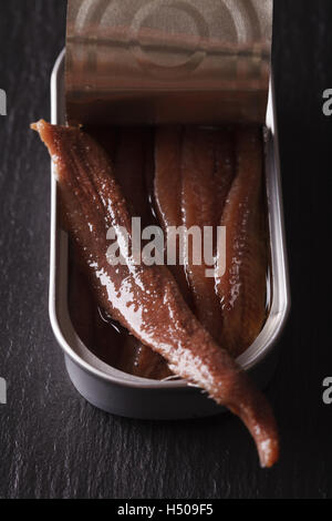Filets d'anchois dans tin macro sur un conseil d'ardoise. vertical Banque D'Images