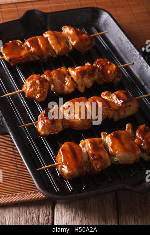 Brochettes de poulet yakitori japonais sur un gril vertical close-up. Banque D'Images