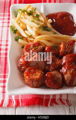 Saucisse Currywurst avec frites gros plan sur une plaque verticale. Banque D'Images