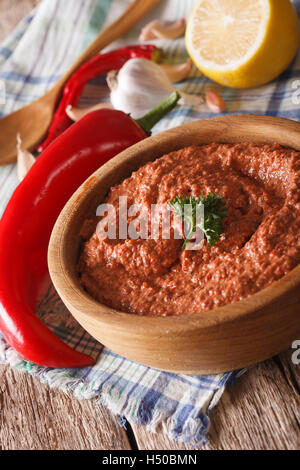 Muhammara rouge snack à bol en bois close-up sur la table verticale. Banque D'Images