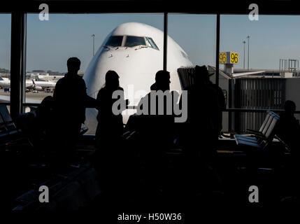 Silhouette de passagers en attente à l'aéroport gate avec le nez d'un avion à l'extérieur, sur le tarmac de l'aéroport. Banque D'Images