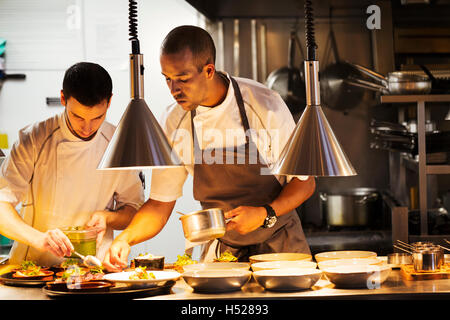 Deux chefs dans une cuisine de restaurant, le placage de la nourriture. Banque D'Images