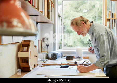 Un luthier à sa planche à dessin faisant ressortir les plans et de l'esquisse d'un nouvel instrument. Banque D'Images