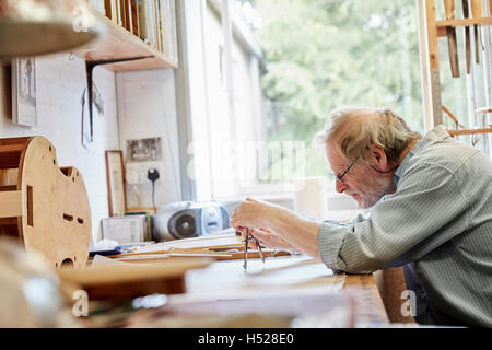 Un luthier à sa planche à dessin faisant ressortir les plans et de l'esquisse d'un nouvel instrument. Banque D'Images