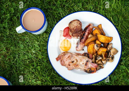 High angle view of English Breakfast sur une assiette et tasse de thé sur une pelouse. Banque D'Images