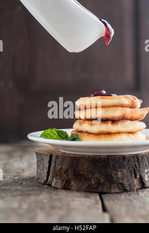 Verser sur la confiture crêpes de fromage cottage en bois sombre sur un arrière-plan. Banque D'Images