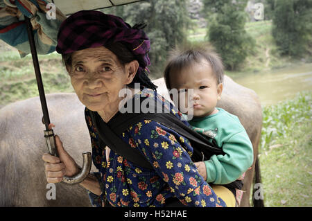 Grand-mère de la minorité ethnique hmong dans la province de Ha Giang portant son petit-fils, le Nord Vietnam Banque D'Images