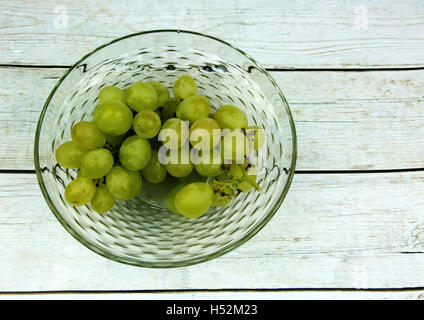 Bouquet de raisin vert dans un bol en verre sur une vieille table en bois dans un style vintage.plate horizontale Vue de dessus. Banque D'Images