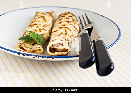 Crêpes crêpes minces laminées menthe sur une plaque avec couteau et fourchette. Banque D'Images