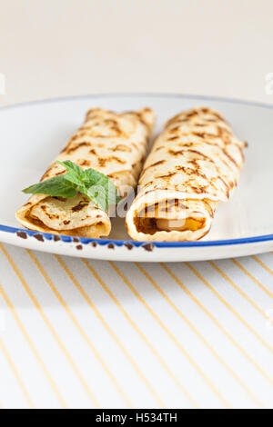 Crêpes crêpes minces laminées menthe sur une plaque avec couteau et fourchette. Banque D'Images