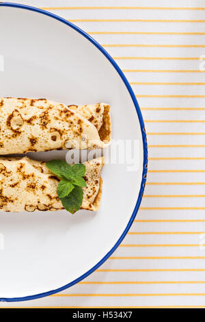 Crêpes crêpes minces laminées menthe sur une plaque avec couteau et fourchette. Banque D'Images