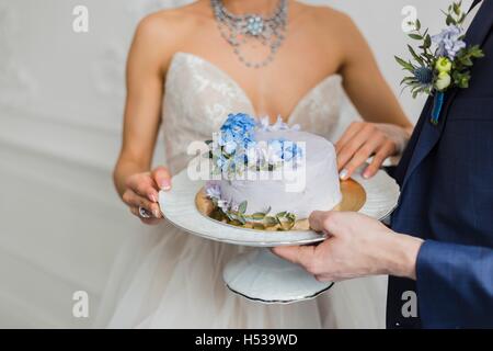 Bride and Groom tenir gâteau de mariage Banque D'Images