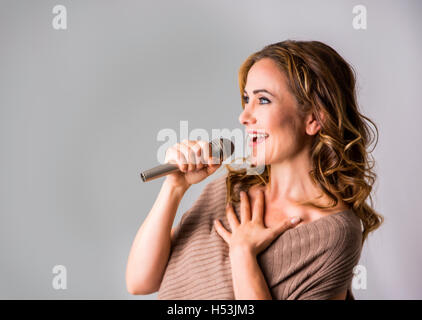 Jolie femme adulte parlant au micro et sourire Banque D'Images