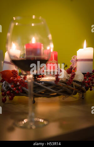 / Noël décoration de l'Avent avec 4 bougies allumées, selective focus, verre de vin rouge à l'avant Banque D'Images