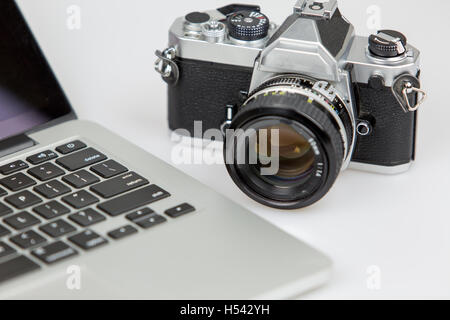 Appareil photo vintage et un ordinateur portable sur un tableau blanc avec fond blanc. film appareil photo de foucs. Banque D'Images