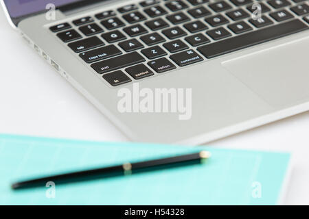 Pc portable avec stylo et bloc-notes dans foregorund hors focus. pen et ordinateur portable hors focus. Banque D'Images