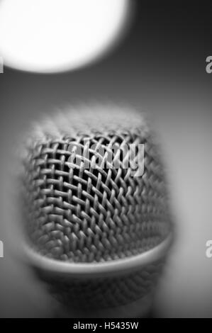 Noir et blanc moderne tête de microphone de studio macro close up avec hors de focaliser la lumière sur le dessus en arrière-plan Banque D'Images