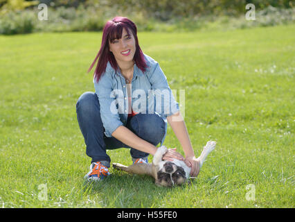 Belle jeune femme avec son chien bouledogue français dans le parc Banque D'Images