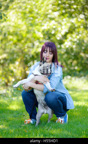 Belle jeune femme avec son chien bouledogue français dans le parc Banque D'Images